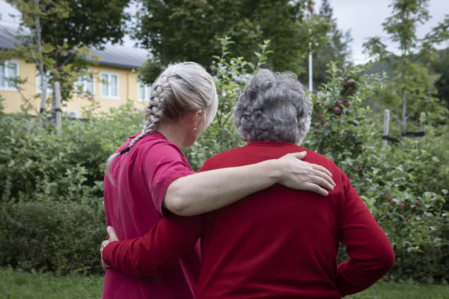 To kvinner avbildes bakfra som omfavner hverandre. Bildet gir en empatisk stemning.